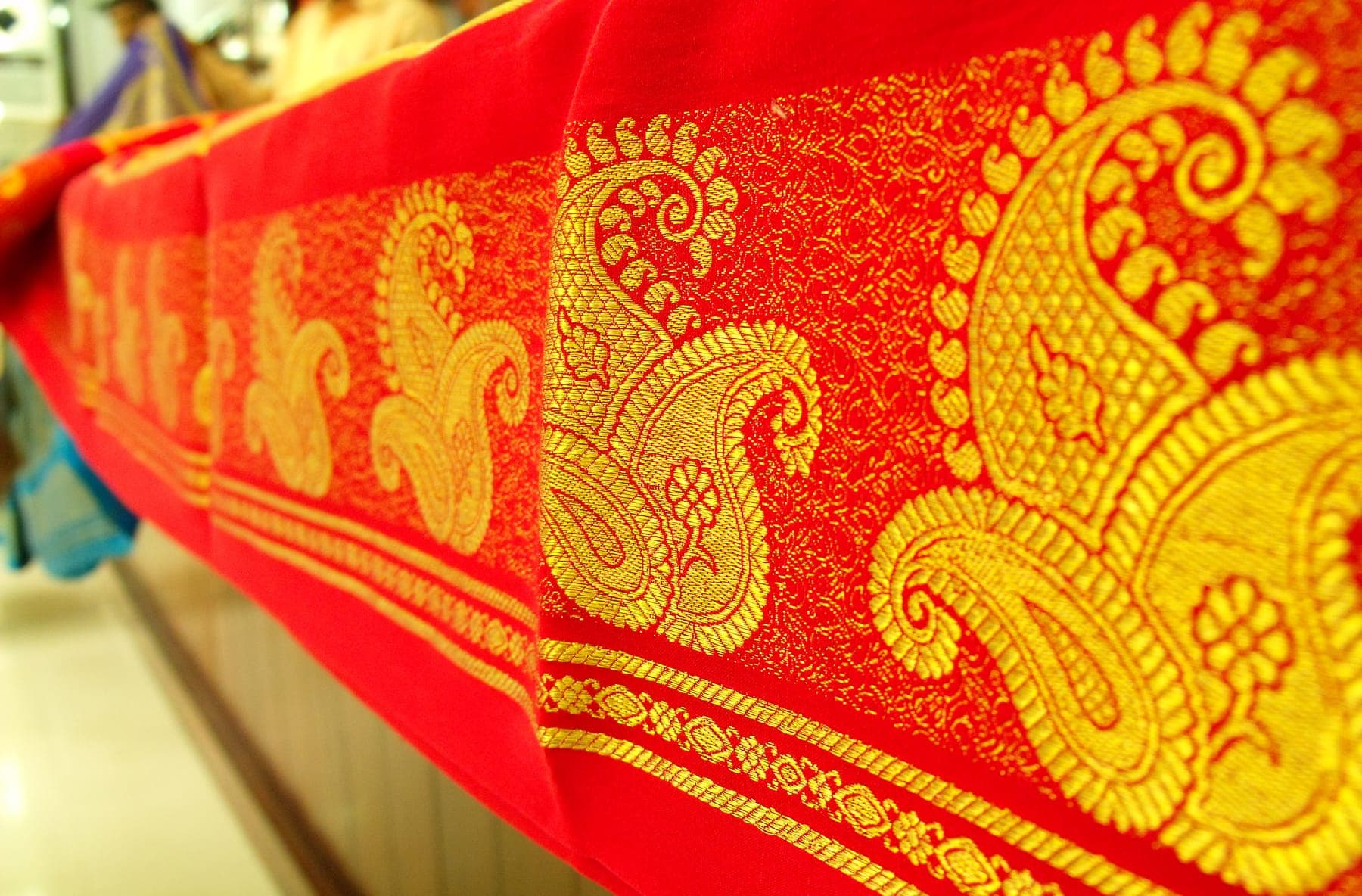 The border of a red silk saree woven with gold zari paisleys